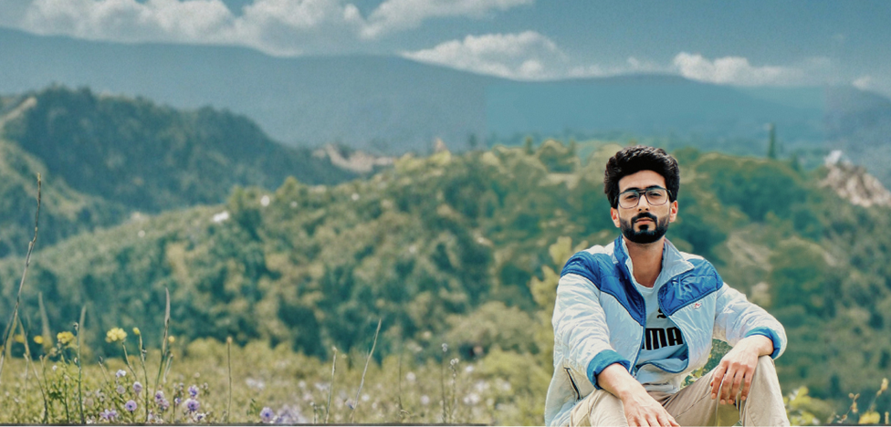 Daarish Dar seated outdoors, hills behind him.